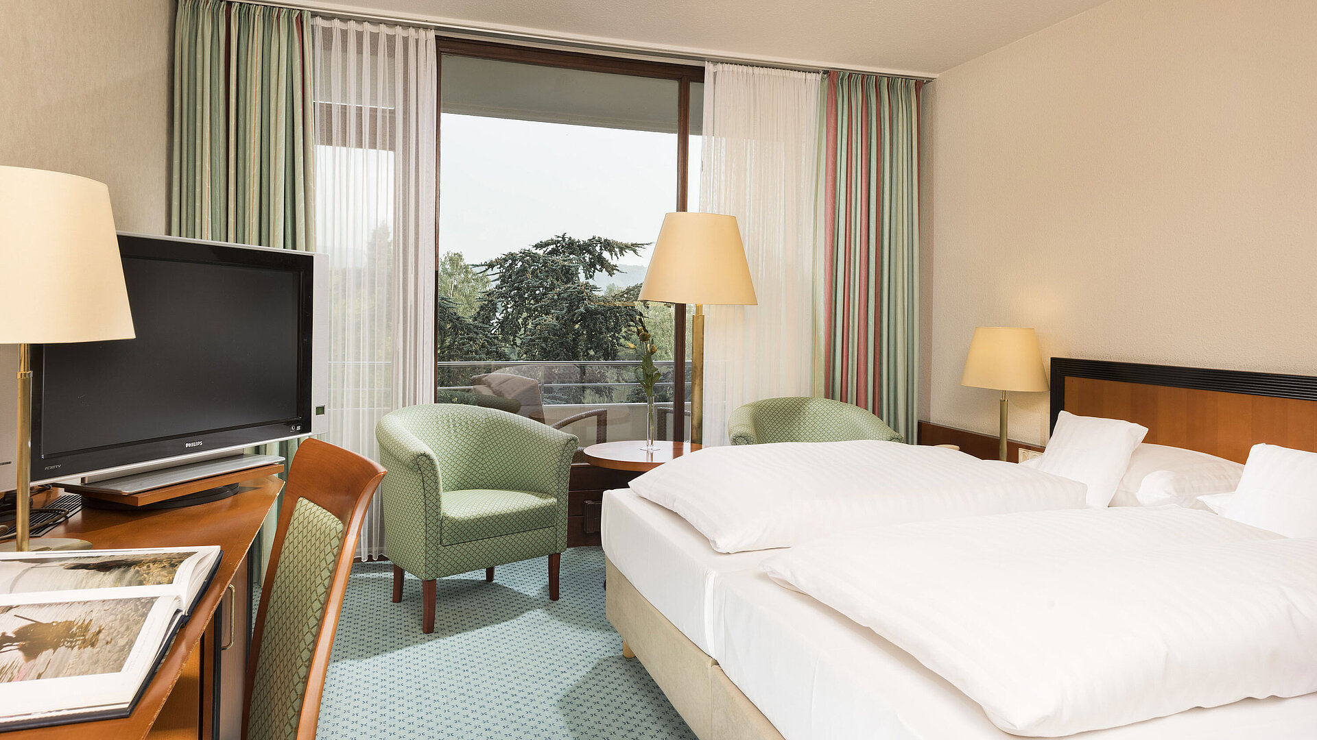 Habitación luminosa en el Maritim Hotel Bad Salzuflen con cama doble, zona de estar y acceso al balcón